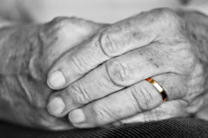 Close up on elderly woman hands with golden wedding ring - loss of a spouse and no financial plan