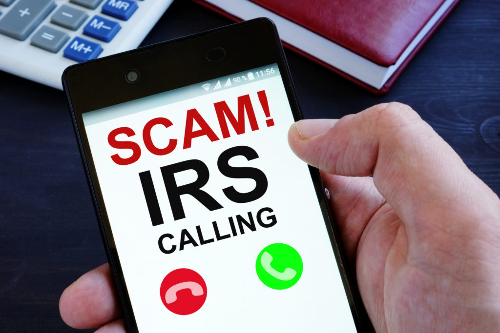 IRS telephone scams showing hand holding phone with scams alert - Stableford Blog