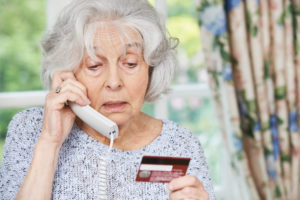 debit or credit card telephone scams showing senior woman on phone giving information - stableford
