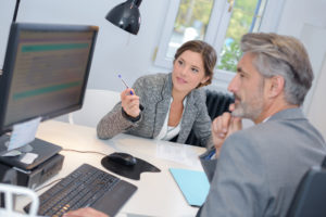 Man sitting at desk talking with woman financial adviser