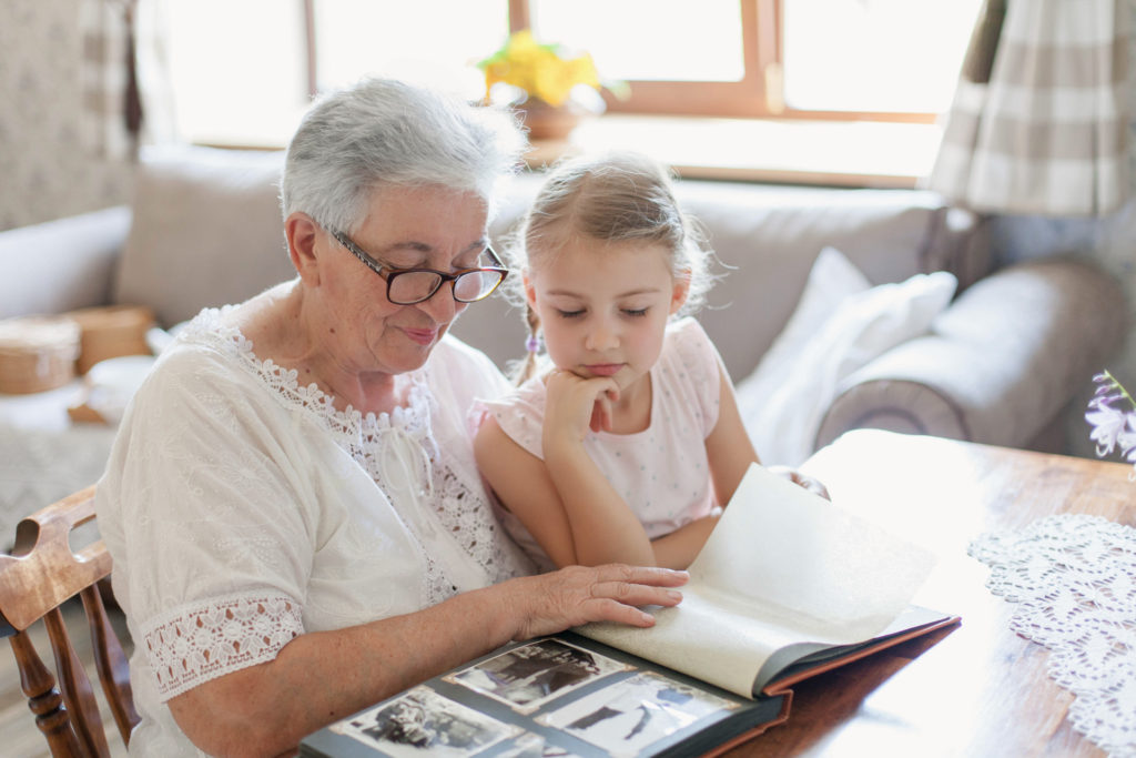 Ethical wills can be used to pass down family heirlooms that have little to no financial value such old family photographs or albums such as this Grandmother and granddaughter looking at black and white photo album