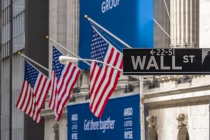 Market Commentary May 2020 Wall St sign with American flags in the background