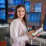 Woman financial advisor working in front of multiple stock market computer screens - wen
