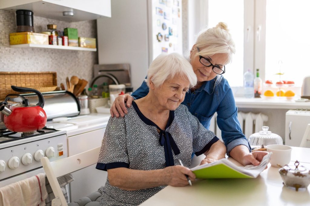 Alzheimer's Financial Planning woman helping elderly woman with paperwork-web