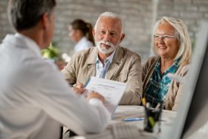 signing up for medicare at age 65 - older couple talking about documents - web
